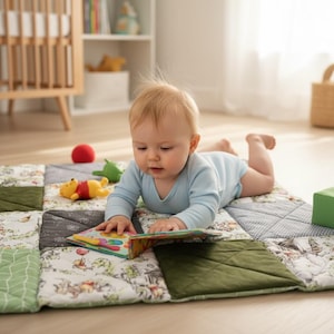 May include: A baby in a light blue onesie lies on a colorful patchwork play mat. The mat features various patterns, including floral and geometric designs, with green and gray squares. A Winnie the Pooh toy and a red ball are nearby.