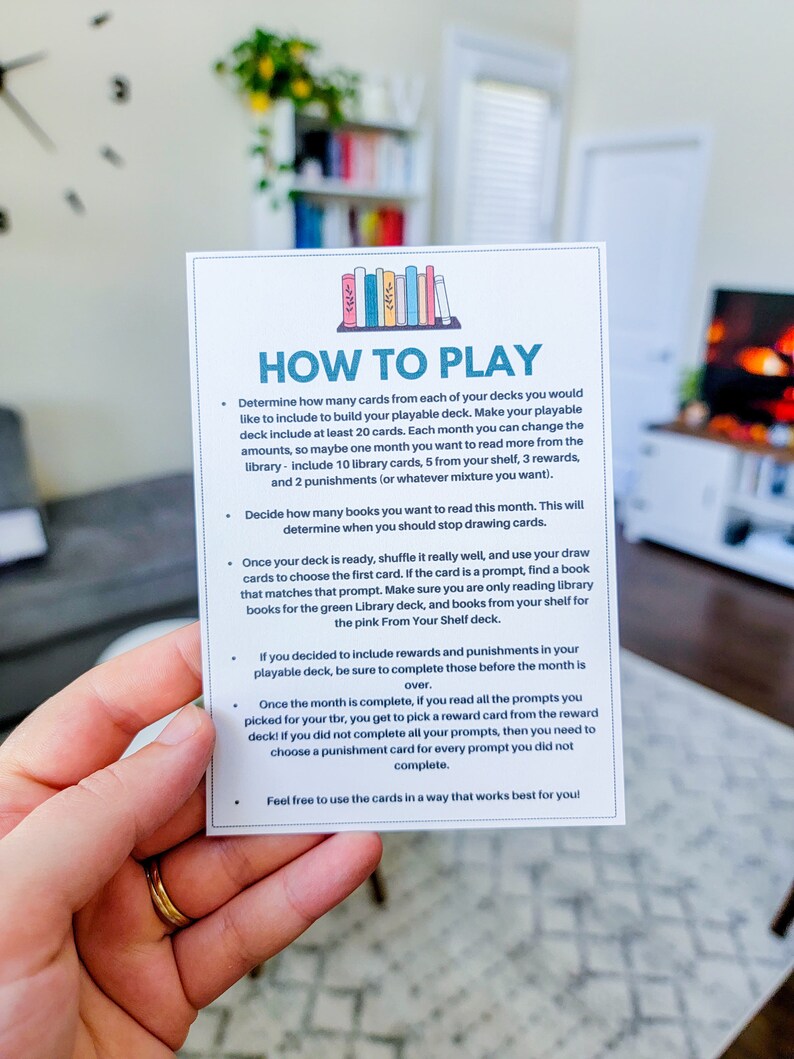 May include: A white card with blue and green text and illustrations of books. The card has instructions on how to play a reading game. The text on the card reads "How to Play".
