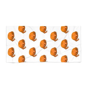 May include: A white rectangular towel featuring a repeating pattern of orange-colored frogs. Each frog is depicted with a textured, bumpy skin surface and is oriented in various directions across the fabric, creating a consistent graphic design.