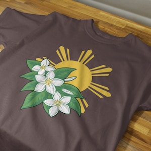 May include: A dark brown t-shirt with a white flower design and a yellow sun with rays, representing the Philippine flag.