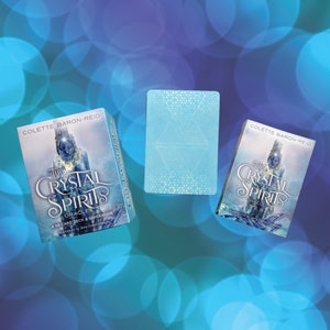 May include: A blue and white oracle deck box with the title "The Crystal Spirits Oracle" and the text "A 58-card deck & guidebook" on the front. The box is open and the cards are visible.