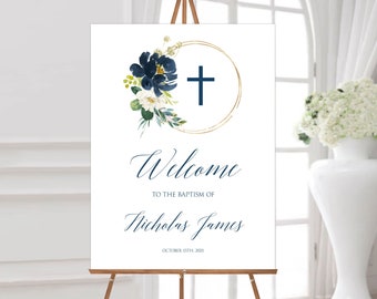 May include: A white welcome sign with a gold circle and a blue cross. The sign has a watercolor floral design in shades of blue and white. The text reads "Welcome to the Baptism of Nicholas James October 15th, 2021".