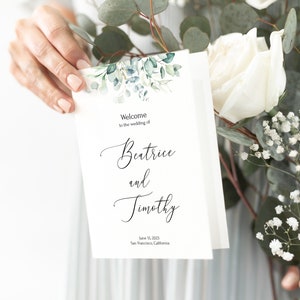 Könnte beinhalten: Hochzeits-Programm mit einem Aquarell-Design aus Eukalyptusblättern. Das Programm lautet "Willkommen zur Hochzeit von Beatrice und Timothy" und enthält das Datum 15. Juni 2023 und den Ort San Francisco, Kalifornien.