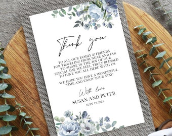 Könnte beinhalten: Eine weiße Dankeskarte mit blauen und grünen Blumenillustrationen. Der Text lautet "Danke" und enthält eine Nachricht, in der die Gäste für ihre Teilnahme an der Hochzeit von Susan und Peter am 19. Juli 2025 bedankt werden.