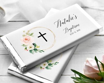 May include: White chocolate bar wrapper with a gold cross and floral design. The text reads "Natalie's Baptism July 11, 2021".