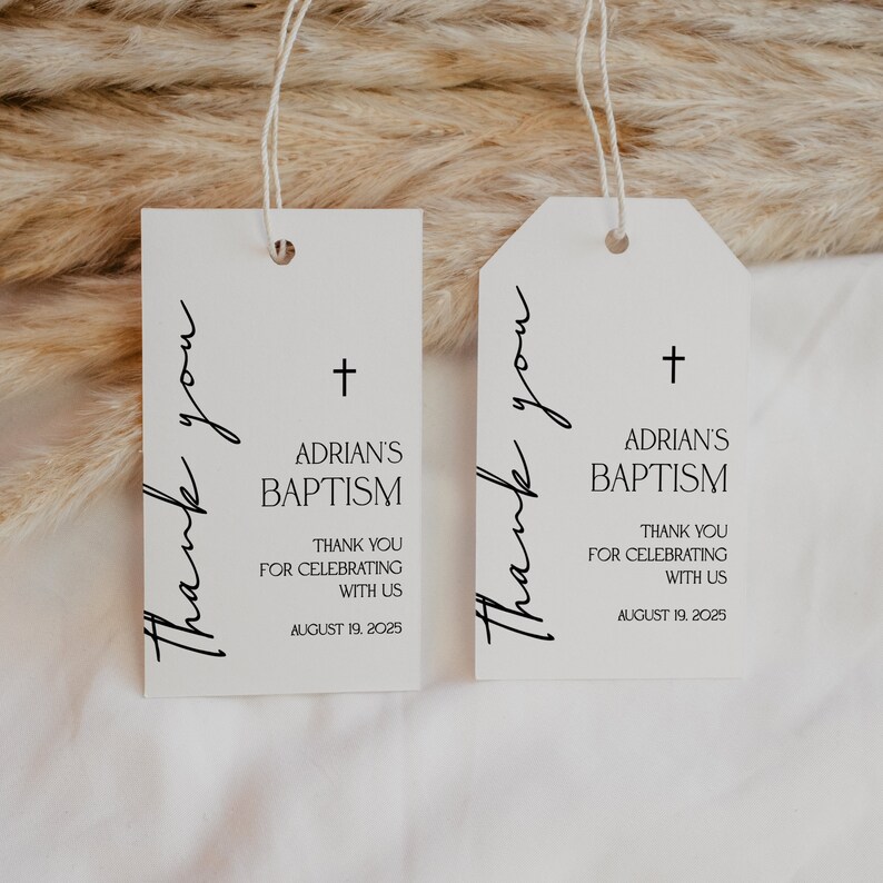 May include: Two white baptism favor tags with the text "Thank you" in a script font. The tags have a cross and the words "Adrian's Baptism", "Thank you for celebrating with us", and the date August 19, 2025.