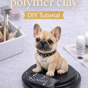 May include: A tan polymer clay French Bulldog sculpture with a black collar and a name tag that says "Bailey". The sculpture sits on a black base. The image includes text that says "Sculpting a Frenchie in polymer clay DIY Tutorial".