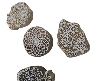 May include: Four wooden printing blocks with intricate white designs. The blocks feature floral, geometric, and paisley patterns. The blocks are various shapes and sizes, perfect for textile art and crafting.