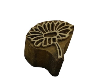 May include: A wooden printing block with a carved design of a flower. The block is brown and the flower is white.