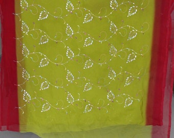 Könnte beinhalten: Ein durchsichtiger, limettengrüner Stoff mit rotem Rand. Der Stoff ist mit einem zarten Muster aus weißen Blättern und Ranken verziert, das mit kleinen, farbigen Perlen akzentuiert ist. Das Design ist symmetrisch und bedeckt den Großteil der Stoffoberfläche.