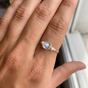 May include: A silver wire wrapped ring with a round iridescent gemstone.