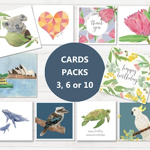 May include: A collection of square greeting cards with watercolor illustrations. Designs include a koala, a geometric heart, protea flowers, the Sydney Opera House, whales, a kookaburra, a turtle, and a cockatoo. Text on some cards reads "thank you", "happy birthday", and "Have a turtley awesome birthday!"