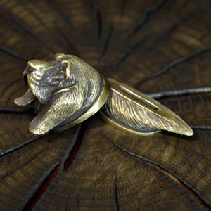 Könnte beinhalten: Eine Bronzeskulptur eines Hundekopfes, wobei der Kopf nach links und der Körper nach rechts zeigt. Die Skulptur ist detailliert und realistisch, mit Fell und Gesichtszügen, die deutlich sichtbar sind.