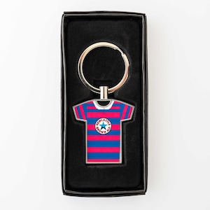 May include: Keyring featuring a miniature soccer jersey with blue and red stripes. The jersey has a circular emblem with text and a star. The keyring is silver and comes in a black box.