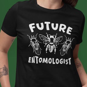 May include: Black t-shirt with the words "FUTURE ENTOMOLOGIST" in white, and insect illustrations. The shirt has a crew neck and short sleeves.