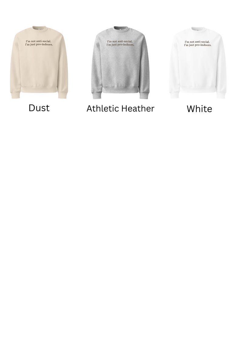 May include: Three crewneck sweatshirts in different colors: dust, athletic heather, and white. Each sweatshirt has the text "I'm not anti-social, I'm just pro-indoors." printed on the front in black.