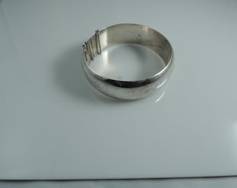 May include: A silver bangle bracelet with a chain detail. The bracelet is smooth and shiny.
