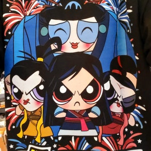 May include: Black t-shirt with a graphic of four cartoon girls in a superhero pose. The girls are wearing colorful outfits and have large eyes. The text "The Hun-Defeating Girls" is printed in yellow with a red heart. The background features red, white, and blue fireworks.