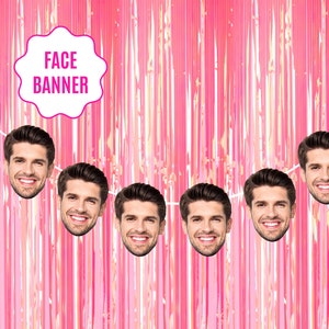 May include: A pink metallic fringe curtain backdrop featuring a repeating cutout of a smiling man's face strung along a white cord. A white scalloped label in the upper left corner contains the pink text FACE BANNER in all capital letters.