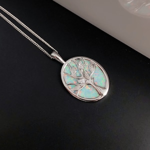 Può includere: Una collana con catena d'argento con un ciondolo ovale che presenta un design ad albero con una pietra di opale bianca e accenti di zircone cubico trasparenti.
