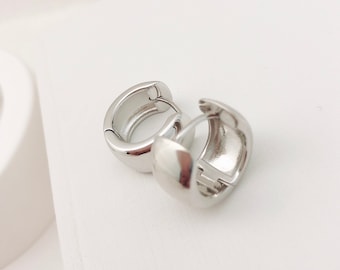 May include: A pair of silver hoop earrings. The earrings are smooth and have a rounded shape.