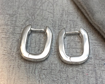 May include: A pair of silver hoop earrings with a rectangular shape. The earrings are simple and elegant.