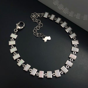May include: A silver bracelet with a chain and rectangular white opal stones.
