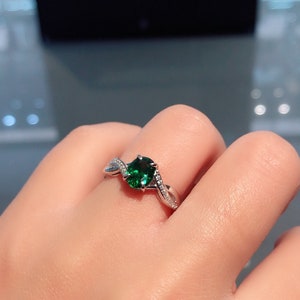 Puede incluir: Un anillo de plata con una piedra preciosa verde y peque&ntilde;as piedras transparentes engastadas en una banda retorcida.