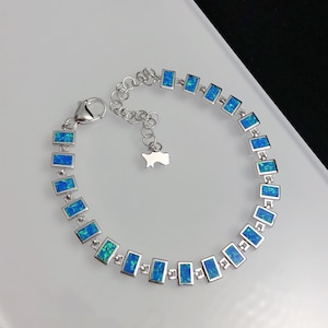 May include: A silver bracelet with a chain and rectangular blue opal stones.