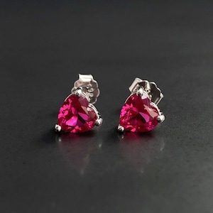 Peut inclure: Une paire de boucles d'oreilles clous en argent en forme de cœur avec des pierres de rubis rouge vif.