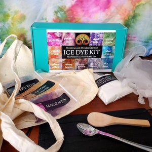 May include: A teal box with the words "Meeting of Minds Studio Ice Dye Kit Professional Non-Toxic Dye" on the front. The box contains a variety of dye colors, including sky blue, golden yellow, magenta, and soda ash. The kit also includes a white cotton bag, two spoons, and a black mat.