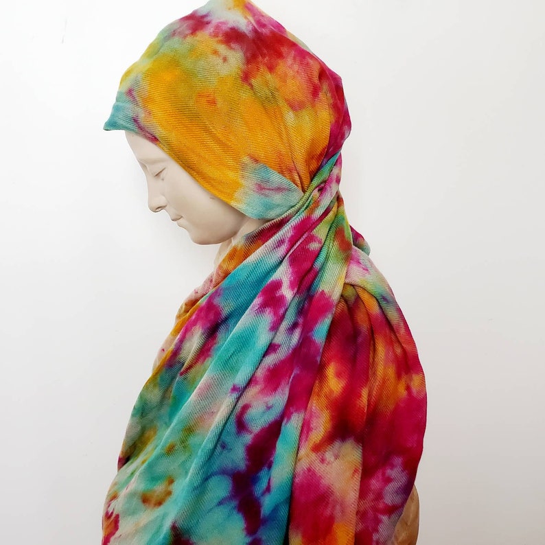 K&ouml;nnte beinhalten: Ein Batik-Schal in den Farben Pink, Gelb, Blau und Gr&uuml;n. Der Schal ist aus einem weichen, dehnbaren Stoff gefertigt und perfekt, um jedem Outfit einen Farbtupfer zu verleihen.