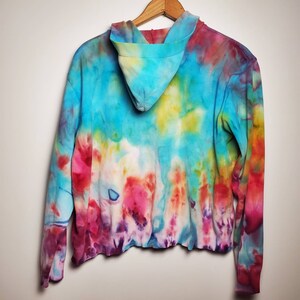 May include: A tie-dye hoodie with a blue, yellow, red, and purple color scheme. The hoodie has a long sleeve and a hood.