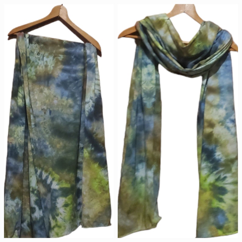 K&ouml;nnte beinhalten: Ein gr&uuml;n-blau-gelber Batik-Schal. Der Schal ist in der H&auml;lfte gefaltet und &uuml;ber einen Kleiderb&uuml;gel gelegt.