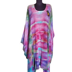 May include: A long, flowing, tie-dye tunic with a scoop neck. The tunic is made of a soft, lightweight fabric and features a colorful, abstract design in shades of pink, purple, blue, and green.