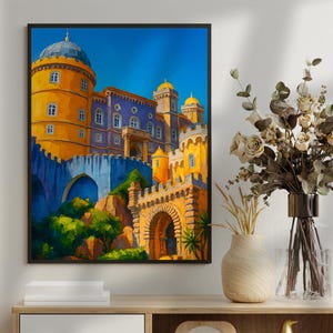 May include: A framed painting depicting a vibrant castle with a blue sky. The artwork showcases yellow, orange, and blue architectural elements. The painting is displayed on a wooden cabinet, alongside decorative items.