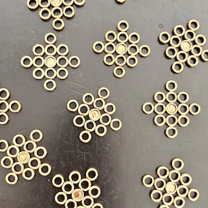 Peut inclure: Une collection de onze composants métalliques dorés, chacun présentant un motif en grille en forme de losange composé de petits anneaux circulaires. Chaque pièce possède un centre circulaire plein entouré de douze anneaux plus petits.