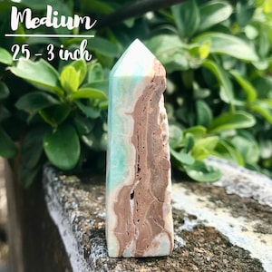 May include: A medium-sized, light blue and brown crystal point, approximately 2.5-3 inches tall. The crystal has a pointed top and a flat base. It is a natural crystal with a unique pattern of light blue and brown layers.