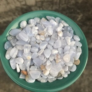 Puede incluir: Un bol lleno de piedras de &aacute;gata azul de encaje azul claro y blanco. Las piedras son lisas y pulidas, y tienen una variedad de formas y tama&ntilde;os.