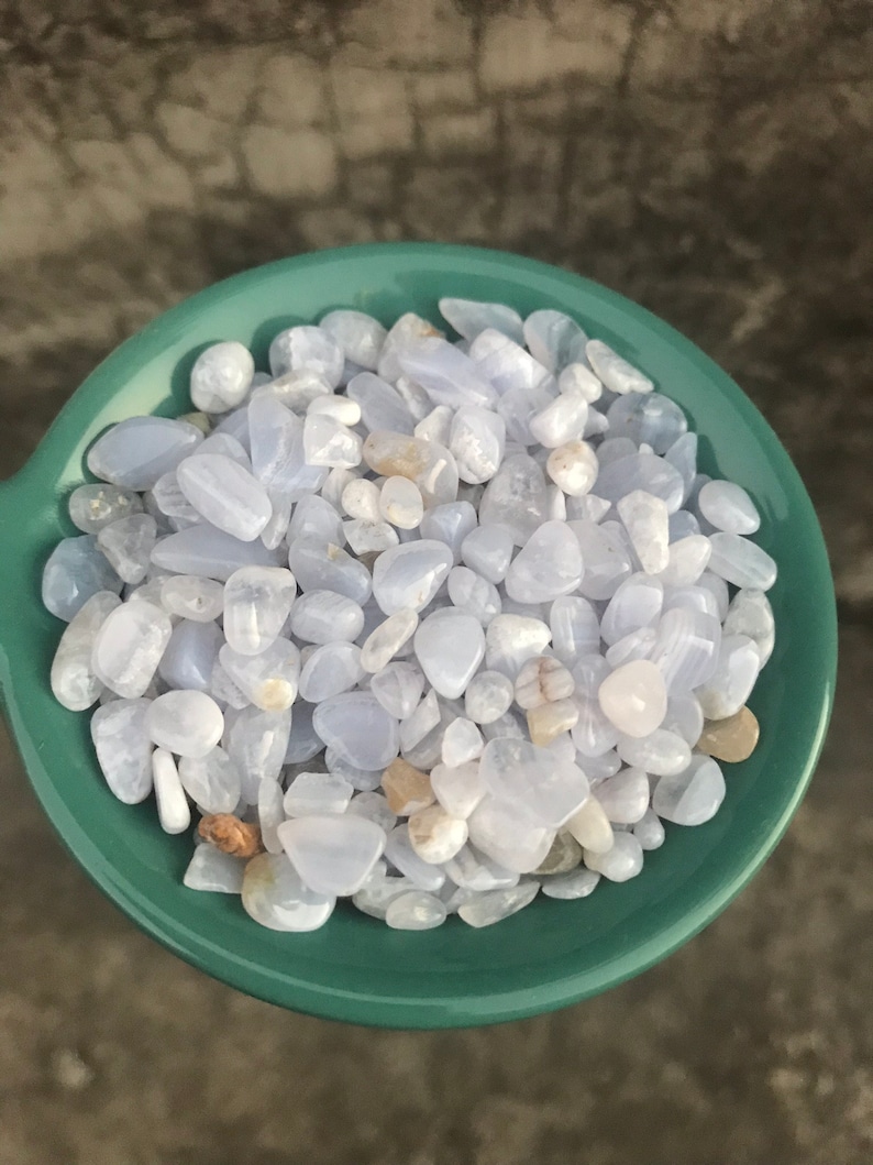Puede incluir: Un bol lleno de piedras de &aacute;gata azul de encaje azul claro y blanco. Las piedras son lisas y pulidas, y tienen una variedad de formas y tama&ntilde;os.