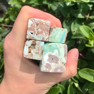 May include: Four small, square, polished, green, brown, and white gemstone blocks. The blocks are stacked on top of each other.