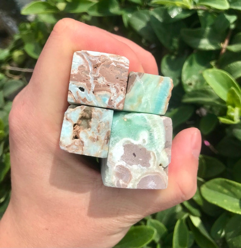 May include: Four small, square, polished, green, brown, and white gemstone blocks. The blocks are stacked on top of each other.