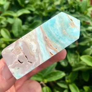 May include: A light blue and brown crystal point with a smooth, polished surface. The crystal has a unique, swirling pattern of light blue and brown.