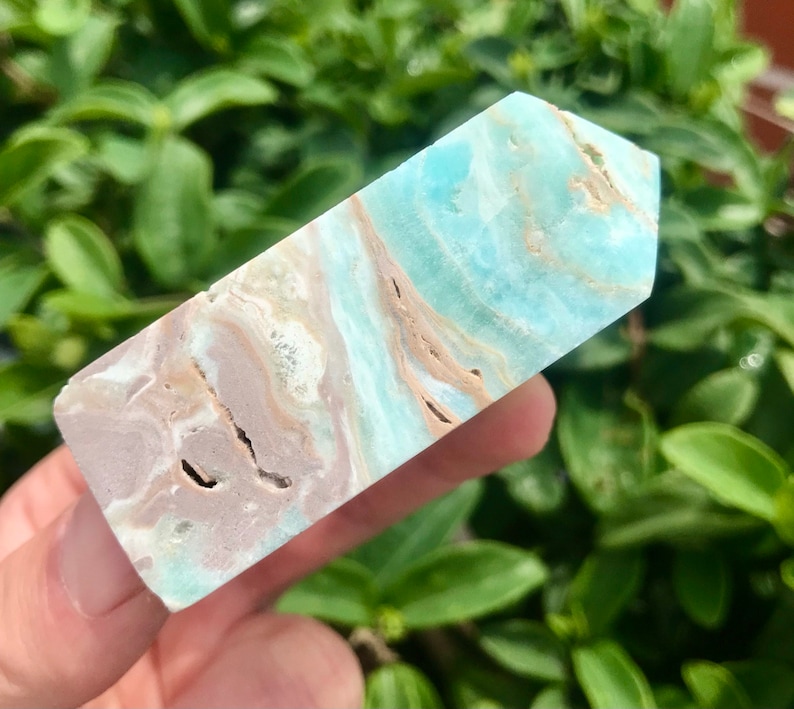 May include: A light blue and brown crystal point with a smooth, polished surface. The crystal has a unique, swirling pattern of light blue and brown.