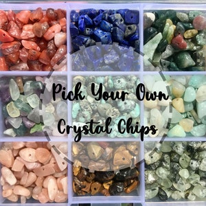 May include: Assortment of small crystal chips in various colors, including red, blue, green, brown, and white. The crystals are arranged in a grid of ten compartments. The text "Pick Your Own Crystal Chips" is superimposed on the image.