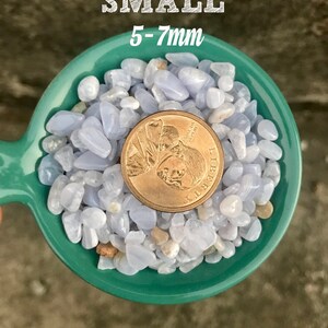 Puede incluir: Primer plano de un cuenco de cer&aacute;mica azul verdoso lleno de peque&ntilde;as piedras pulidas de color azul claro y blanco. Se incluye una moneda de 25 centavos de d&oacute;lar estadounidense como referencia de tama&ntilde;o. El texto "SMALL 5-7mm" est&aacute; escrito encima del cuenco.