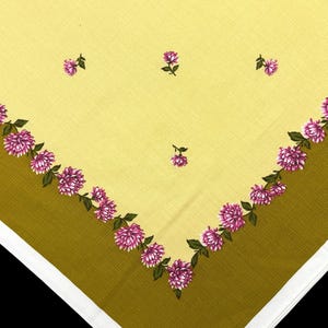 May include: A square fabric handkerchief featuring a pale yellow center with a scattered pattern of small pink chrysanthemum flowers. The border is a solid olive green, accented by a continuous row of pink chrysanthemum blossoms and green leaves.