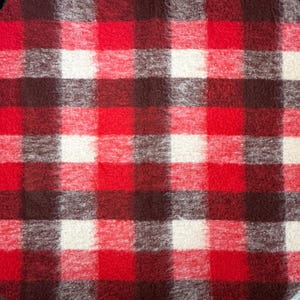 May include: A red, white, and brown plaid blanket. The blanket features a classic checkered pattern with large squares of red, white, and varying shades of brown. The fabric appears soft and textured.