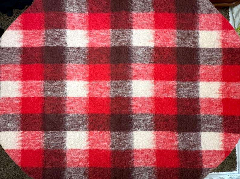May include: A red, white, and brown plaid blanket. The blanket features a classic checkered pattern with large squares of red, white, and varying shades of brown. The fabric appears soft and textured.
