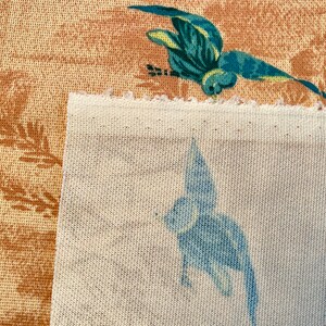 May include: Two fabric swatches, one with a brown background and a blue bird design, and the other with a white background and a blue bird design.